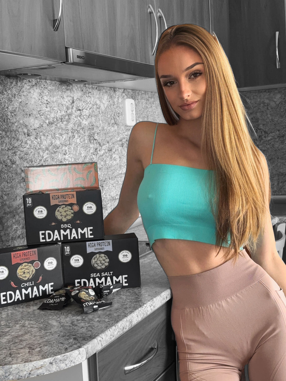 Fiatal nő a konyhában DABEAN pirított edamame dobozokkal