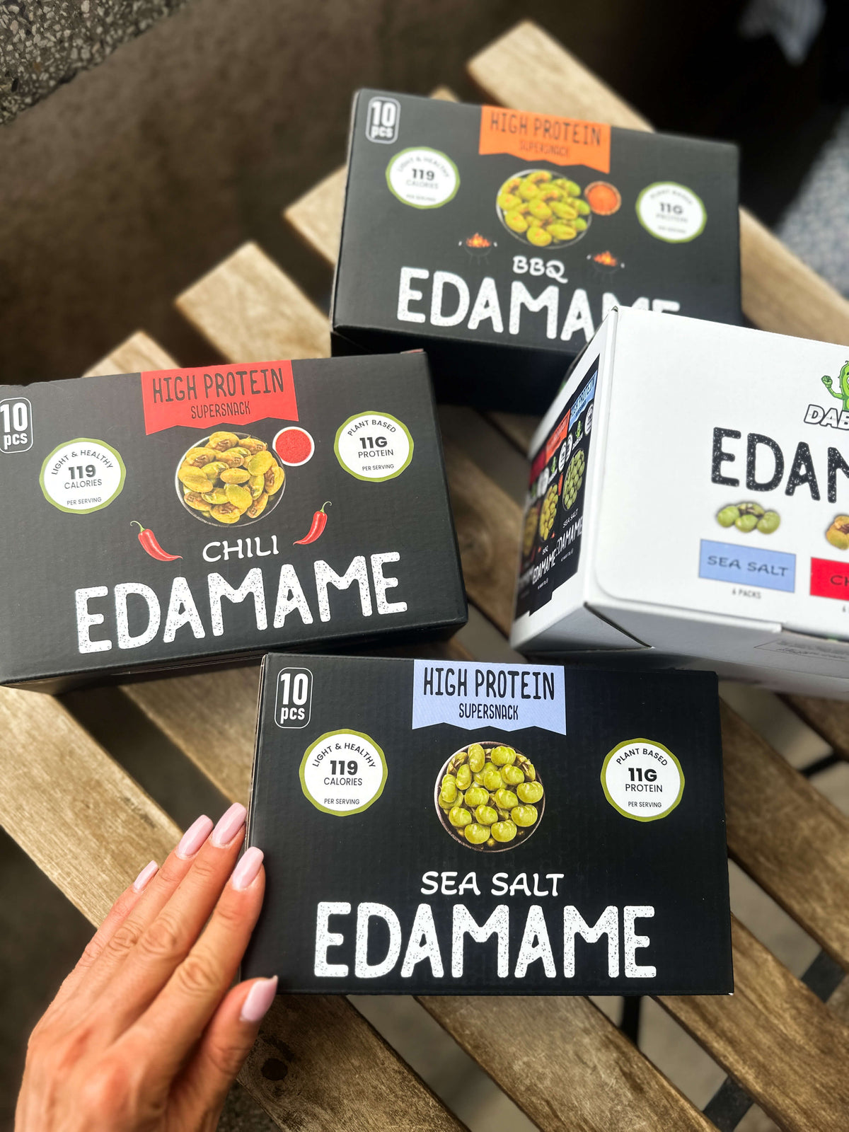 DABEAN edamame dobozok tengeri sós, BBQ és chilis ízben egy fa asztalon
